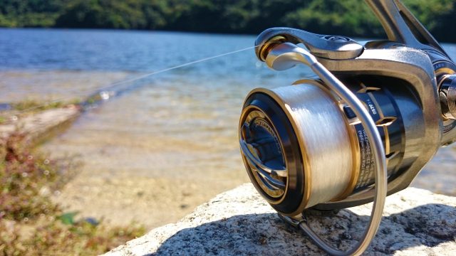 水辺の岩に置いたスピニングリールのアップ