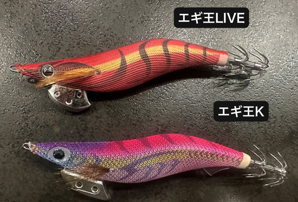 黒い床に2本のエギを並べた写真。上が赤とオレンジのエギ王LIVE パッションレッドで、頭の下に丸く埋まったシンカー。下がピンクと紫のエギ王K ムラムラチェリーで、頭の下に穴の開いたシンカーとお腹の後ろに透明なヒレ